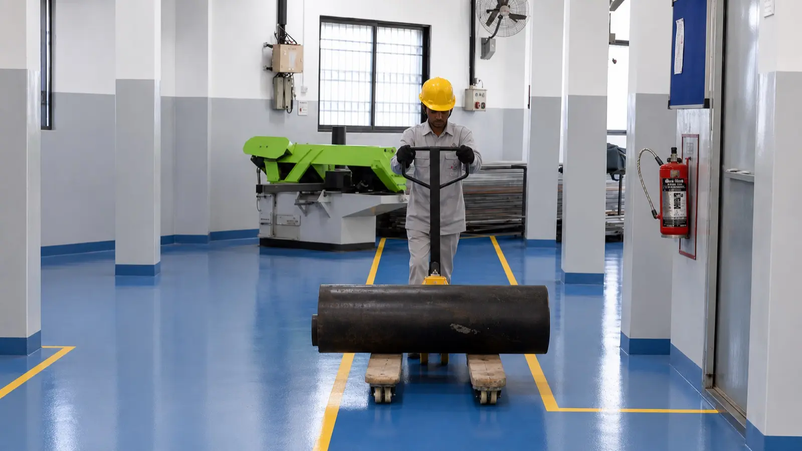 Worker moving industrial component on factory floor